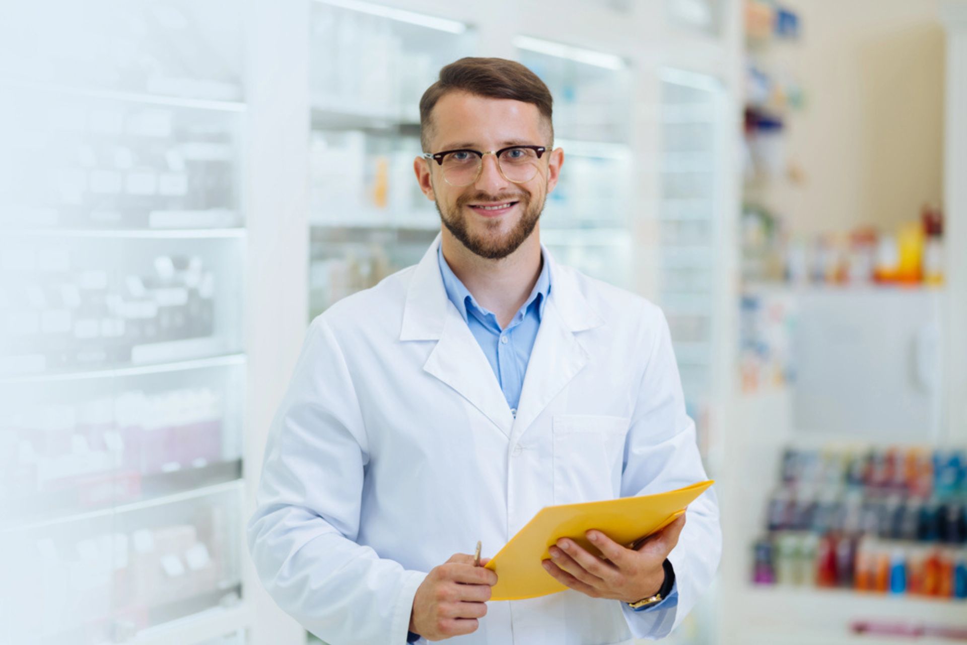 Pharmacien souriant tenant un dossier dans une officine – Illustration de la gestion des non-conformités en pharmacie grâce à la digitalisation.